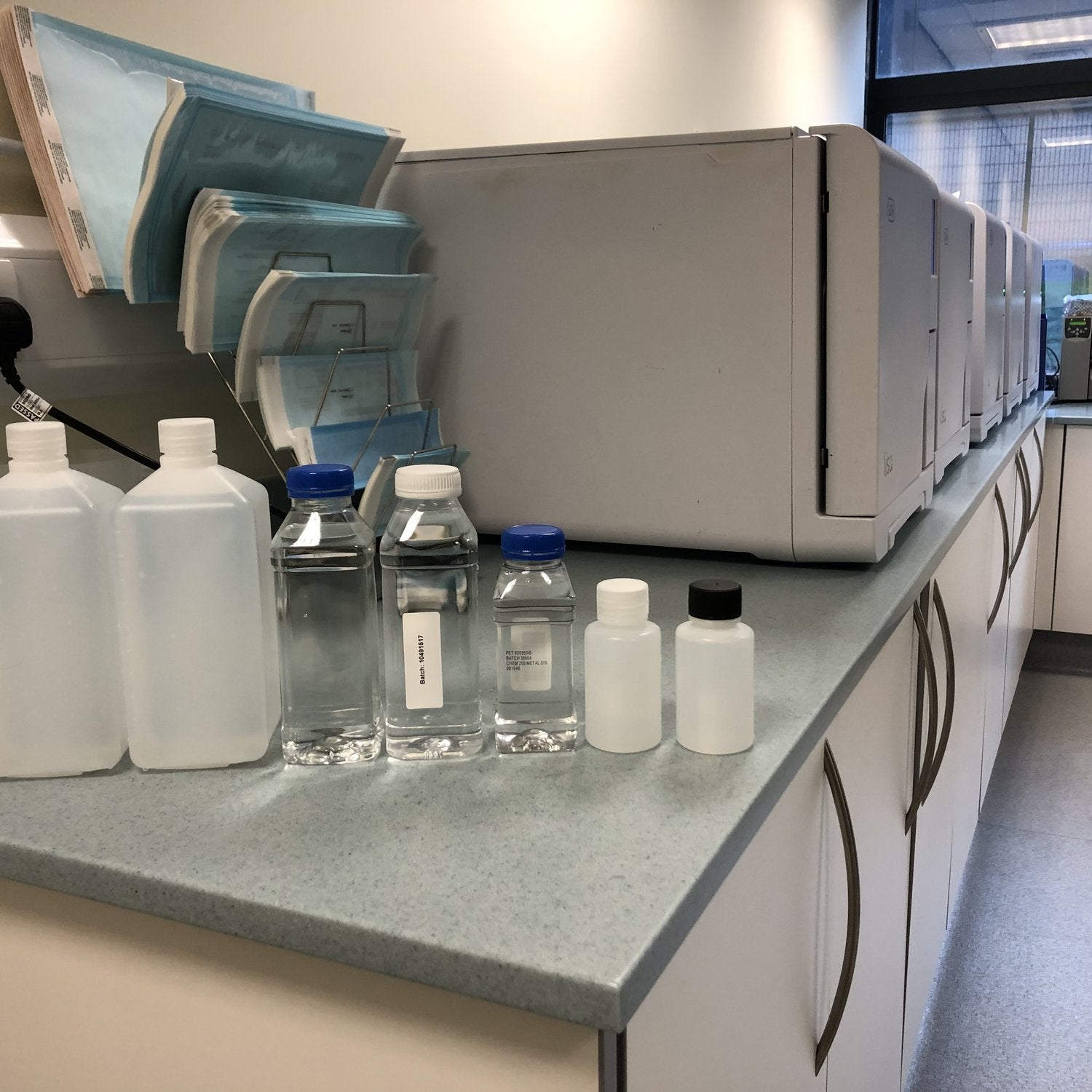 Laboratory sample bottles on the worktop next to the autoclaves